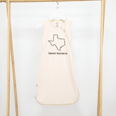 Beige tank top with Texas outline and text on a hanger against a white background