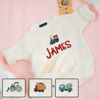 White sweater with embroidered name and train design on a pink background