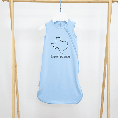 Light blue sleeveless shirt with Texas outline and text on a wooden hanger against a white background