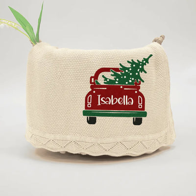 Beige personalized baby blanket with red truck and Christmas tree design, featuring the name 'Isabella'.