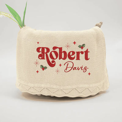 Beige personalized baby blanket with embroidered text 'Robert Davis' on a light gray background