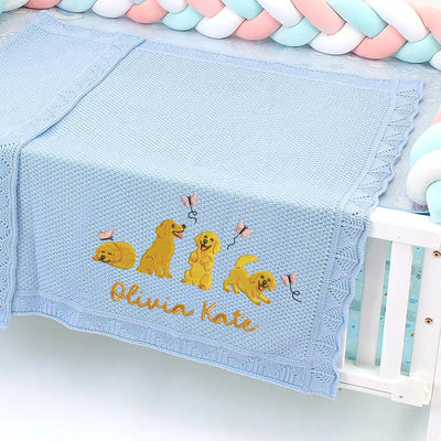 Blue personalized baby blanket with embroidered golden retrievers and 'Olivia Kate' text, placed on a crib.