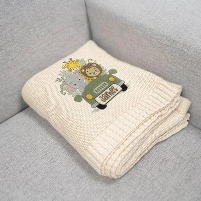 Cream personalized baby woodland adventure blanket with cartoon animals on a gray couch
