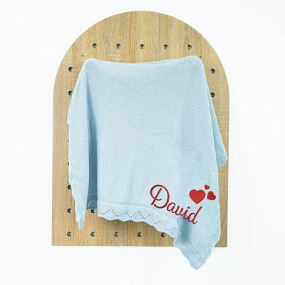 Light blue personalized baby blanket with 'David' and heart designs on a wooden surface