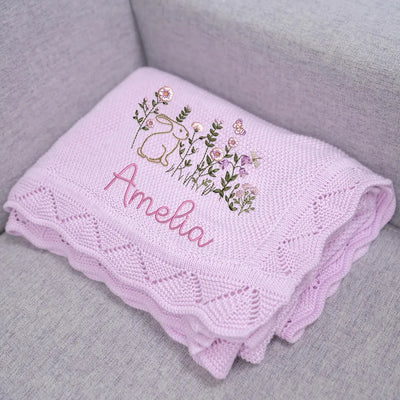 Lilac personalized baby blanket with bunny floral embroidery and 'Amelia' text on a gray surface