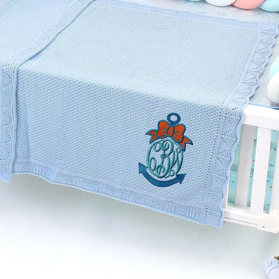 Light blue personalized baby blanket with a anchor design on a crib