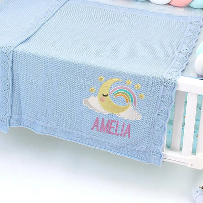 Blue personalized baby blanket with embroidered moon, rainbow, cloud,and stars design, featuring the name 'Amelia'.