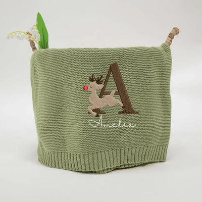 Sage green personalized blanket with embroidered reindeer alphabet design and name on a white background